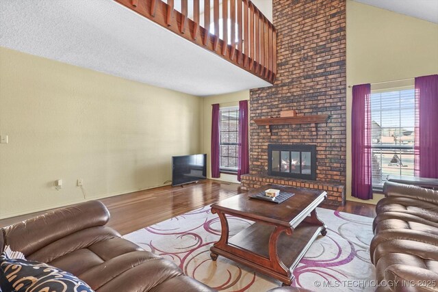 living room featuring a high ceiling, a brick fireplace, and light wood-type flooring