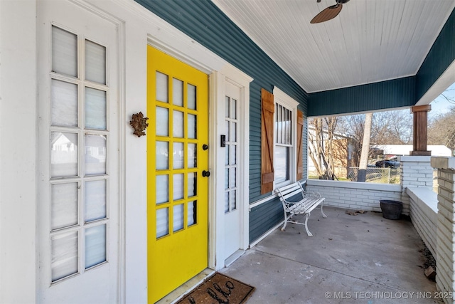 view of exterior entry with ceiling fan and a porch