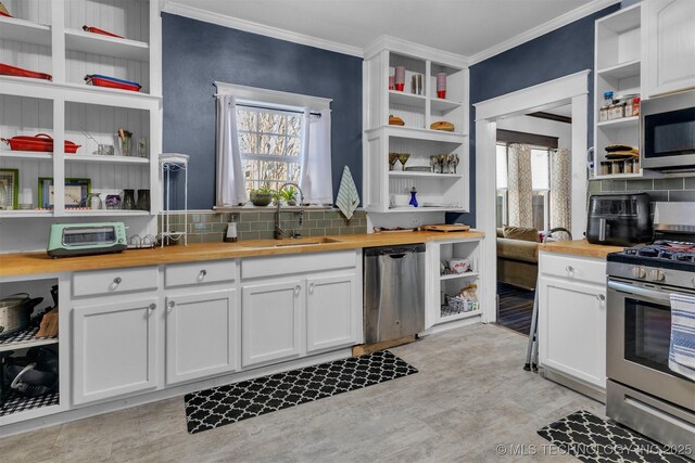 kitchen featuring stainless steel appliances, decorative backsplash, butcher block countertops, crown molding, and white cabinets