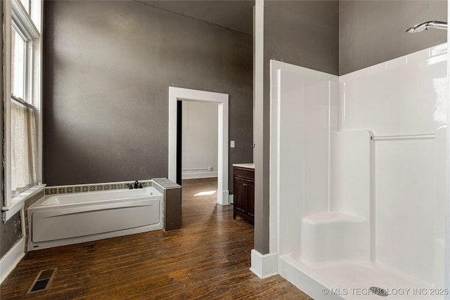 bathroom with hardwood / wood-style flooring, separate shower and tub, and vanity