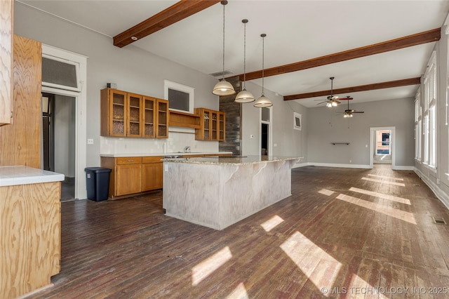 kitchen featuring dark wood-type flooring, pendant lighting, tasteful backsplash, beam ceiling, and ceiling fan