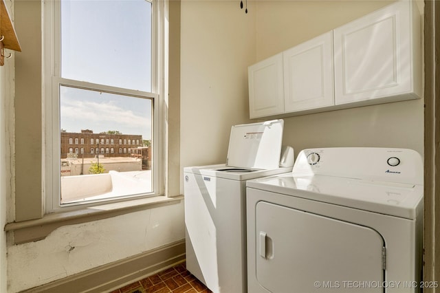 clothes washing area featuring washing machine and dryer and cabinets