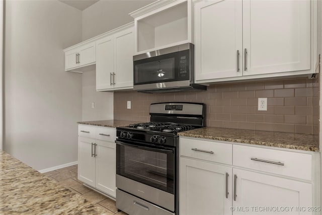 kitchen featuring appliances with stainless steel finishes, dark stone counters, white cabinets, and decorative backsplash