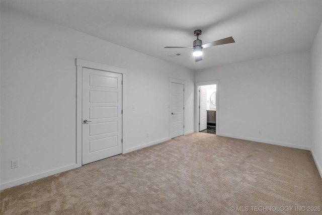 unfurnished bedroom featuring ceiling fan, light colored carpet, and ensuite bath