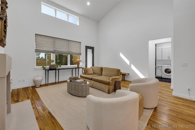 living room with a towering ceiling, washer / clothes dryer, a wealth of natural light, and light hardwood / wood-style flooring