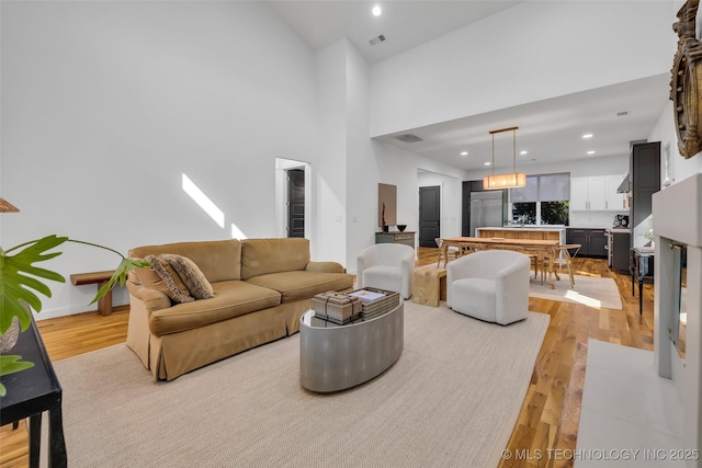 living room featuring light wood-type flooring and a towering ceiling