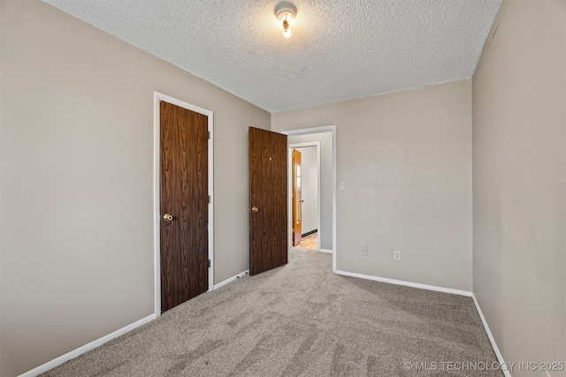 unfurnished room with light colored carpet and a textured ceiling