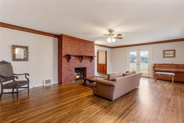 living room with ceiling fan, a brick fireplace, ornamental molding, and hardwood / wood-style flooring