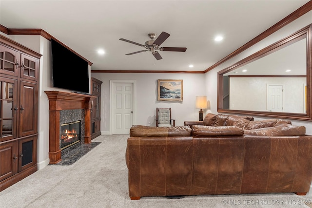 living room featuring a fireplace, ornamental molding, ceiling fan, and light colored carpet