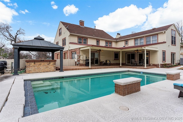 rear view of house featuring ceiling fan, exterior bar, a patio, and a gazebo