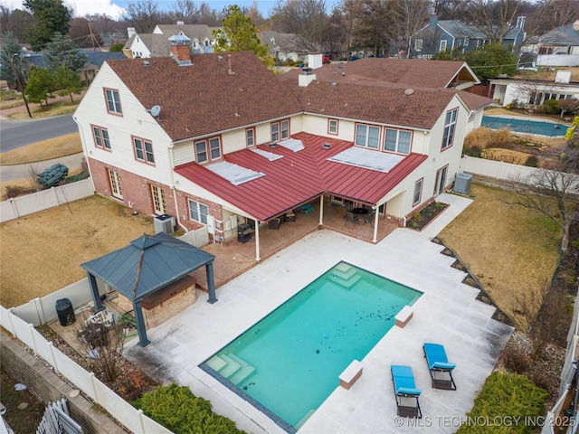 back of property with a lawn, a gazebo, a patio area, and a fenced in pool