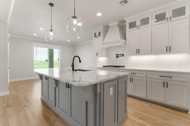 223 W 172nd St S, Mounds, OK 74047 - kitchen featuring premium range hood, decorative backsplash, a kitchen island with sink, white cabinets, and light wood-style flooring