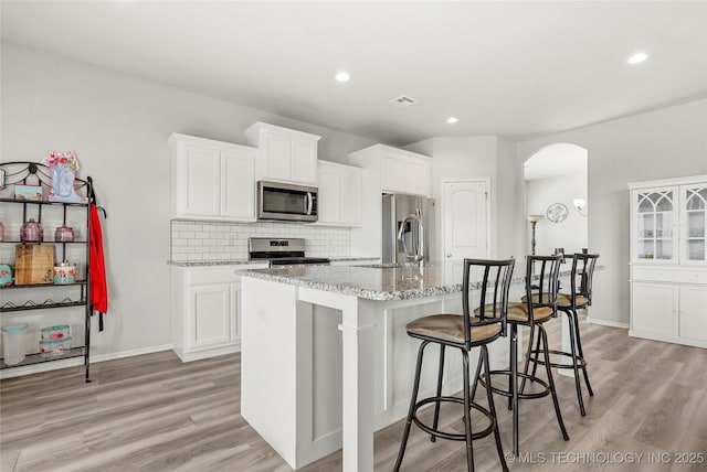 kitchen featuring sink, a center island with sink, appliances with stainless steel finishes, and white cabinetry