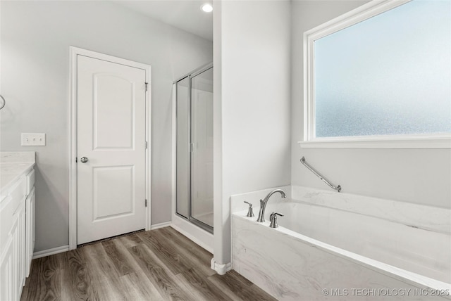 bathroom with plus walk in shower, vanity, and hardwood / wood-style floors