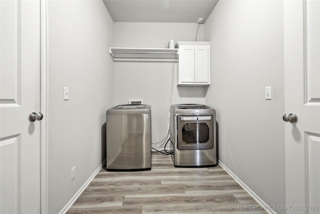 washroom featuring light hardwood / wood-style floors, cabinets, and washing machine and clothes dryer