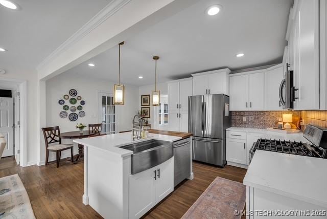 kitchen with sink, white cabinets, hanging light fixtures, a kitchen island with sink, and appliances with stainless steel finishes