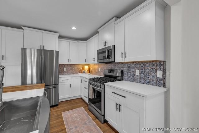 kitchen with stainless steel appliances, white cabinets, dark hardwood / wood-style flooring, and decorative backsplash