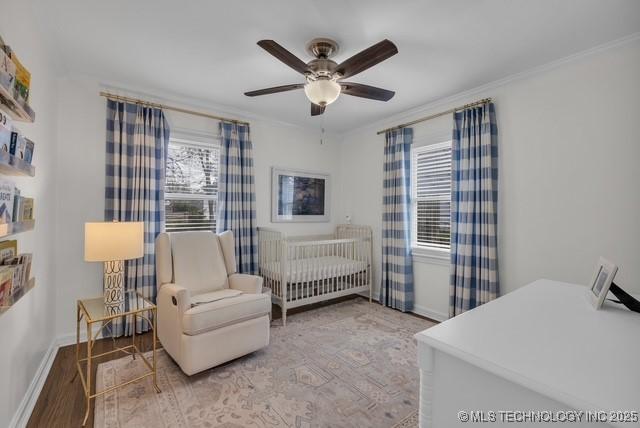 bedroom with ceiling fan, a crib, light hardwood / wood-style floors, and multiple windows