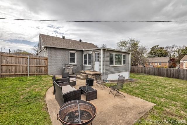 back of house featuring a lawn, an outdoor fire pit, and a patio area