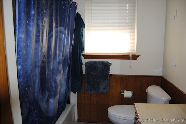 full bathroom with toilet, vanity, wood walls, and shower / bath combination with curtain