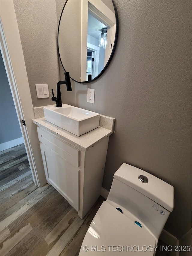 bathroom featuring toilet, vanity, and hardwood / wood-style flooring