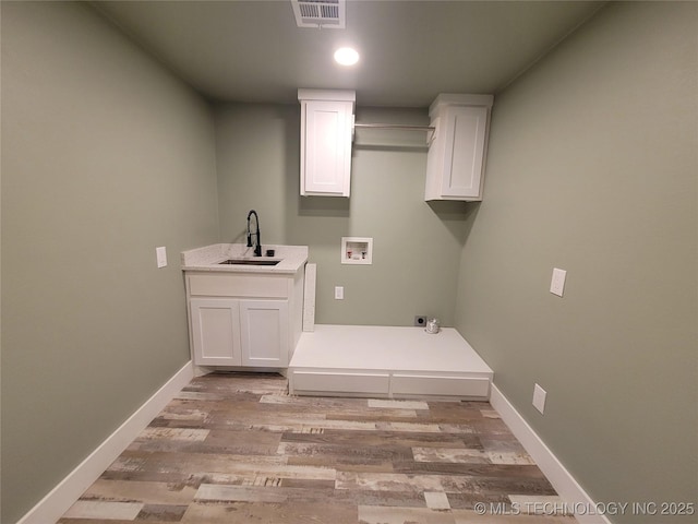 clothes washing area featuring light hardwood / wood-style floors, sink, hookup for a washing machine, hookup for an electric dryer, and cabinets