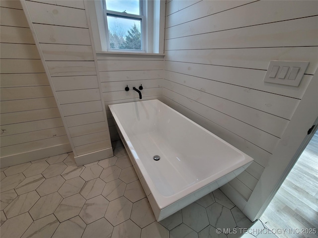 bathroom featuring a bathtub and wood walls