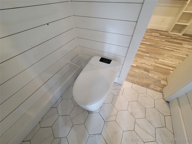 bathroom with toilet and wooden walls