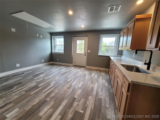 kitchen featuring a textured ceiling, light stone countertops, wood-type flooring, and sink