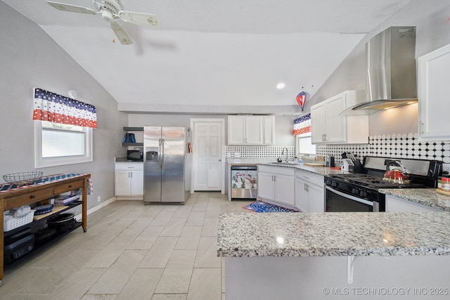 kitchen featuring stainless steel appliances, white cabinetry, wall chimney exhaust hood, lofted ceiling, and tasteful backsplash