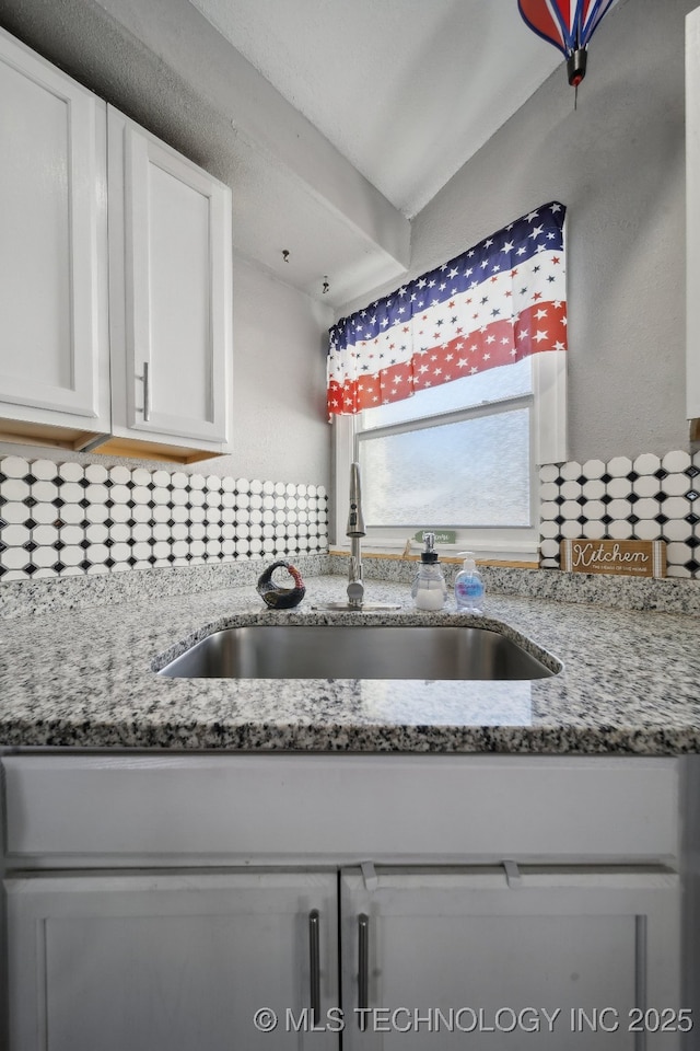 kitchen with sink, white cabinets, and stone counters