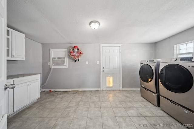 laundry room featuring washer and dryer, a textured ceiling, and cabinets