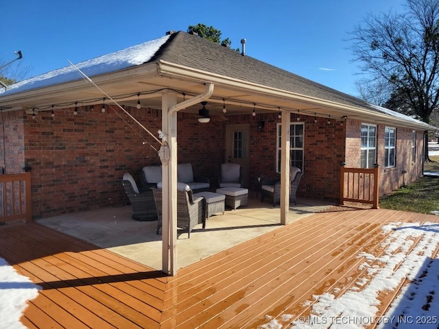 snow covered deck featuring a patio area, ceiling fan, and an outdoor living space