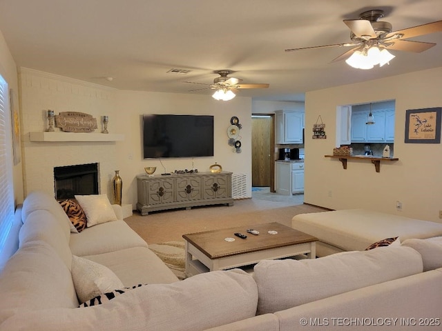 carpeted living room featuring a brick fireplace and ceiling fan