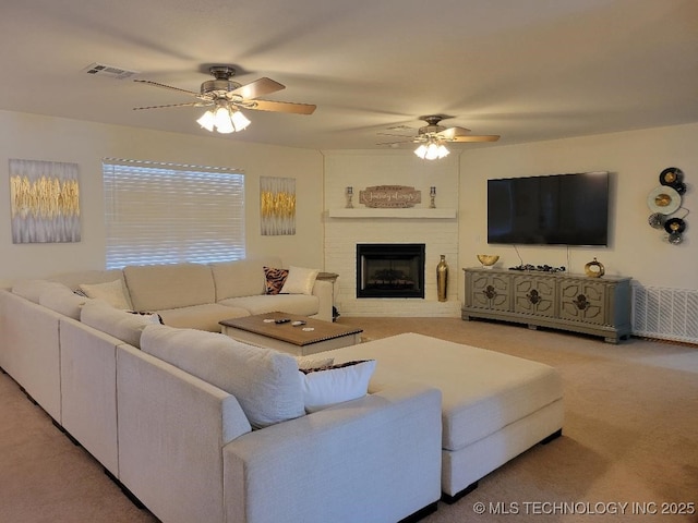 living room featuring a fireplace, carpet floors, and ceiling fan