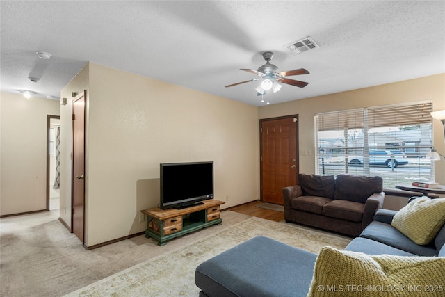 carpeted living room featuring ceiling fan and a textured ceiling