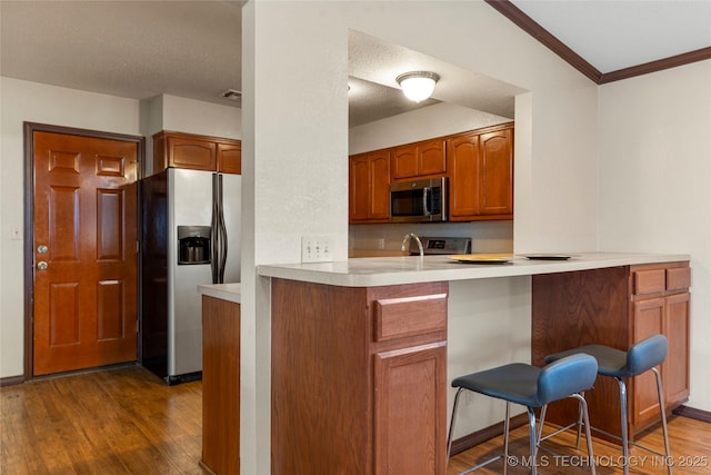 kitchen with lofted ceiling, dark hardwood / wood-style flooring, kitchen peninsula, and appliances with stainless steel finishes