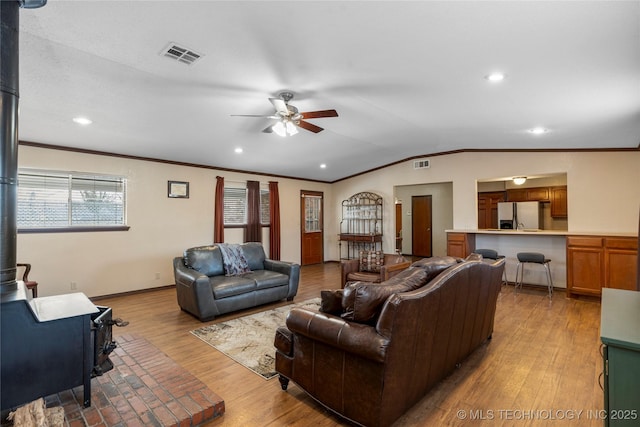 living room with lofted ceiling, ceiling fan, crown molding, and light hardwood / wood-style flooring