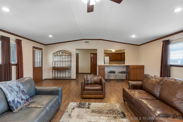 living room with hardwood / wood-style flooring, ceiling fan, vaulted ceiling, and crown molding