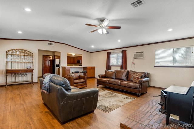 living room featuring a wood stove, lofted ceiling, ceiling fan, light hardwood / wood-style floors, and a wall mounted AC