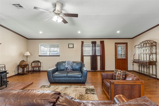 living room featuring ornamental molding, ceiling fan, a wood stove, and hardwood / wood-style floors