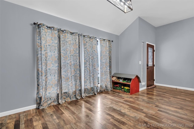 empty room featuring vaulted ceiling, hardwood / wood-style flooring, and a notable chandelier