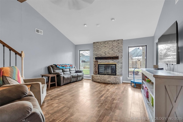 living room with a brick fireplace, high vaulted ceiling, and wood-type flooring