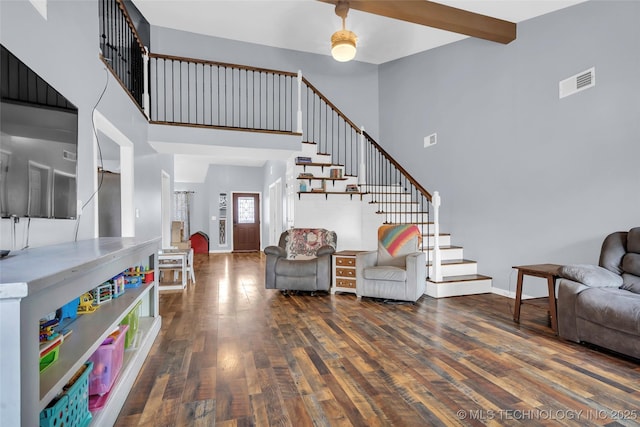 living room featuring beam ceiling, dark wood-type flooring, and a towering ceiling