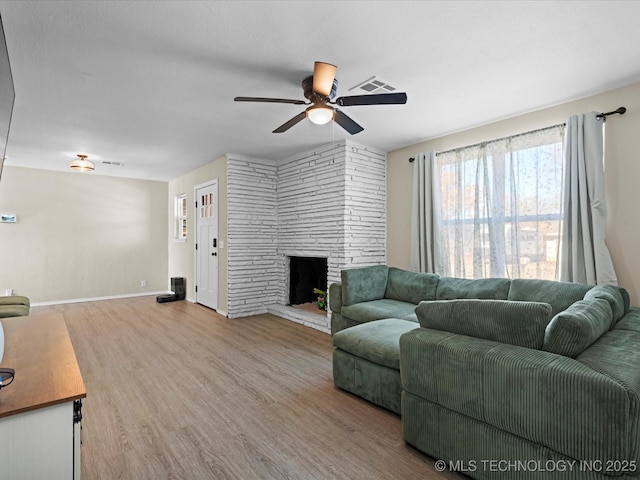 living room with a fireplace, ceiling fan, and light hardwood / wood-style flooring