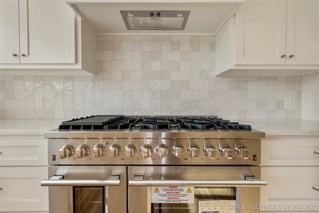 kitchen featuring high end stainless steel range oven, decorative backsplash, white cabinets, and range hood