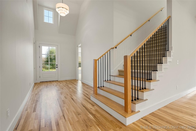 entrance foyer with wood-type flooring and a towering ceiling