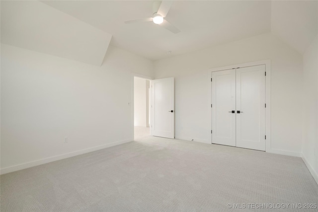 unfurnished bedroom featuring ceiling fan, light carpet, vaulted ceiling, and a closet