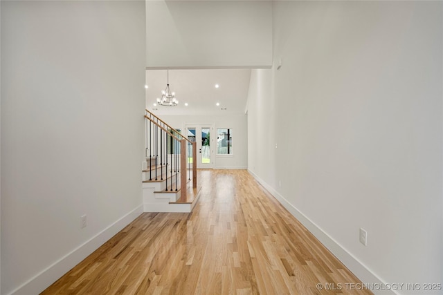 corridor featuring wood-type flooring and a notable chandelier