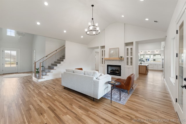 living room featuring light hardwood / wood-style floors, sink, high vaulted ceiling, and a notable chandelier